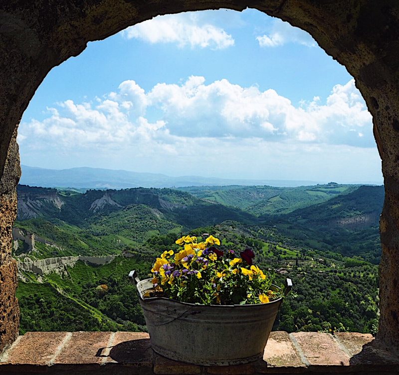 Panorama della Valle dei Calanchi inquadrato da un arco in pietra del borgo di Civita di Bagnoregio