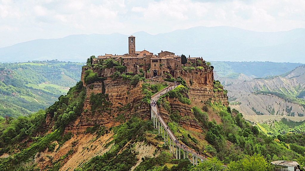 Veduta panoramica di Civita di Bagnoregio al tramonto con il ponte pedonale che collega il borgo ai calanchi