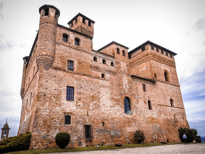 "Il Castello di Grinzane Cavour circondato da vigneti, con architettura medievale in mattoni rossi e torre merlata nelle Langhe Roero e Monferrato"