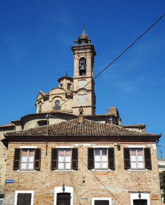 "Borgo medievale di Neive con case in pietra color ocra, situato su una collina circondata da vigneti autunnali”