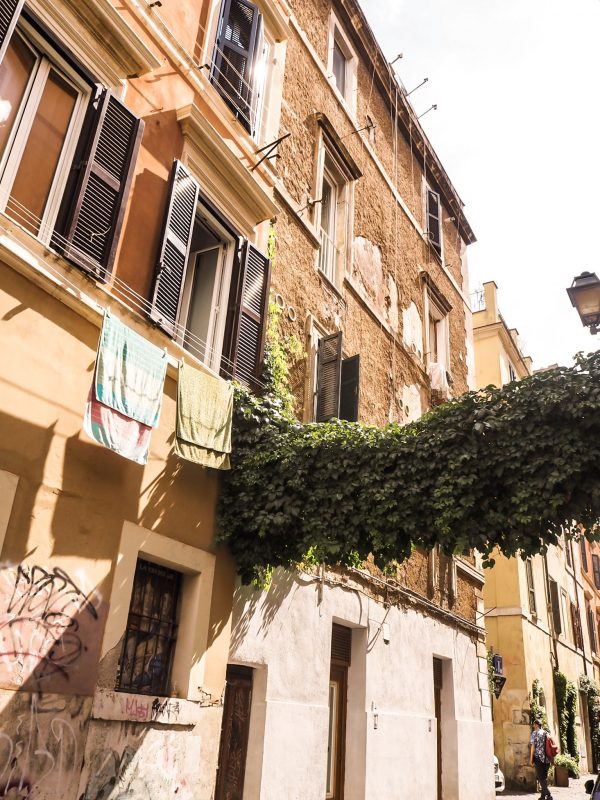 Vicolo storico di Trastevere con case colorate e rampicanti, uno dei quartieri gratuiti di Roma