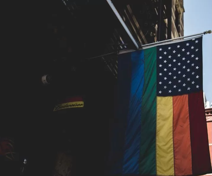 Bandiera arcobaleno LGBTQIA+ con stelle americane appesa a un edificio in una città degli Stati Uniti, simbolo di destinazioni LGBTQIA+ friendly in America