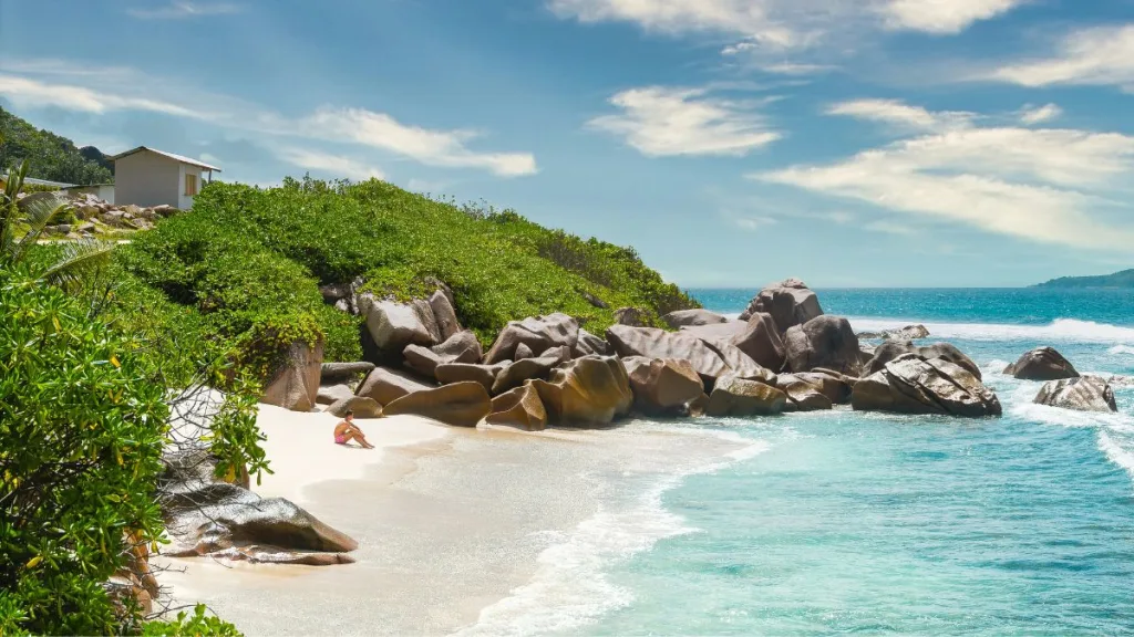 Spiaggia di sabbia bianca con palme e acqua turchese alle Seychelles, destinazione ideale per vacanze ad aprile