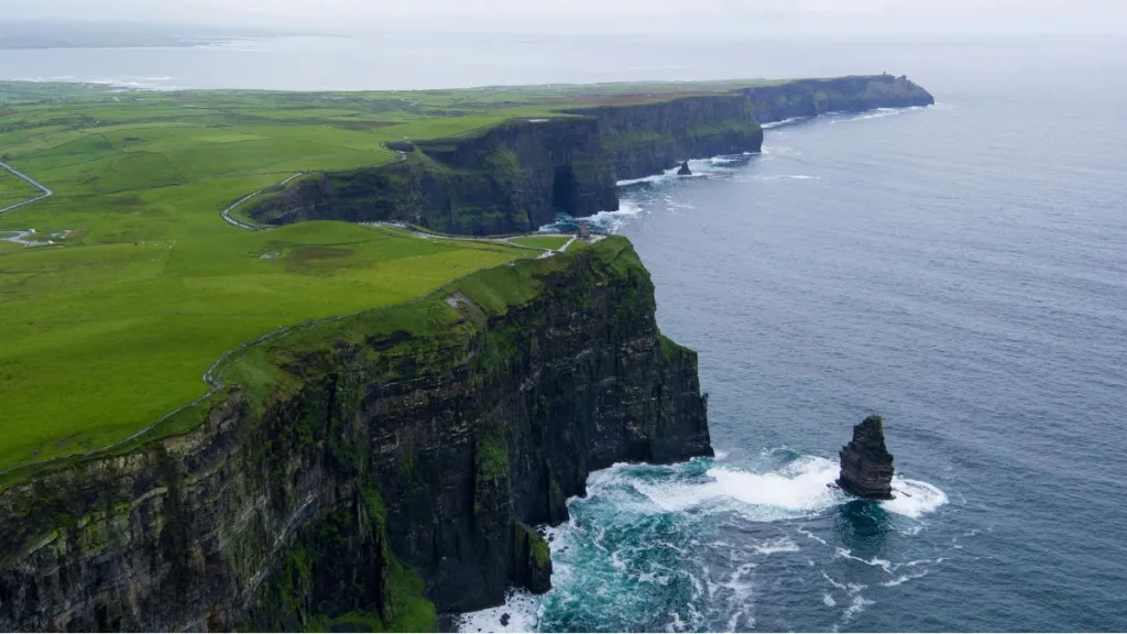 "Scogliera verde in Irlanda con cielo nuvoloso, meta ideale per una vacanza a luglio immersa nella natura"