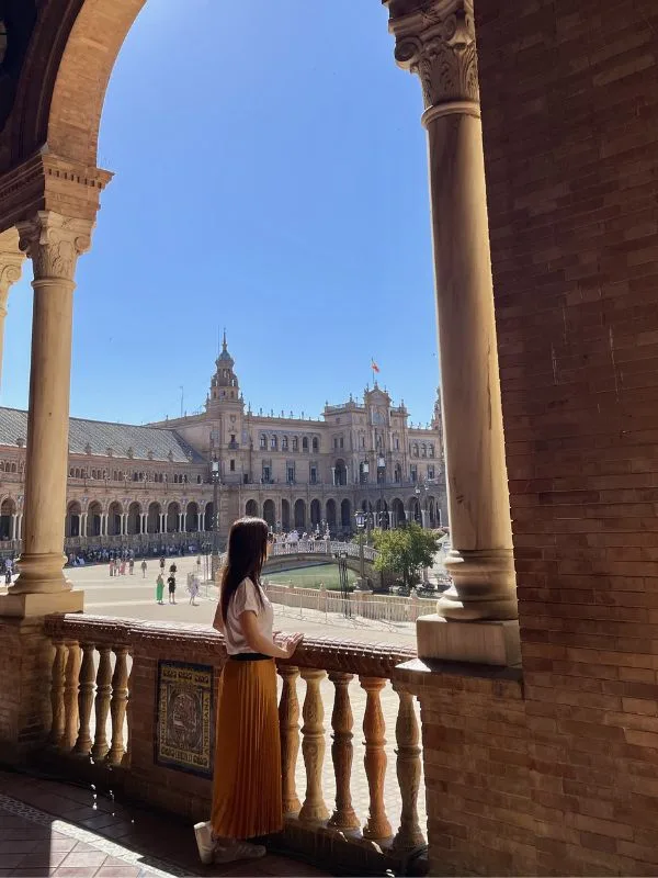 Noemi Bengala con lo sguardo perso nella maestosa Plaza de España di Siviglia, con le ceramiche colorate e il canale semicircolare